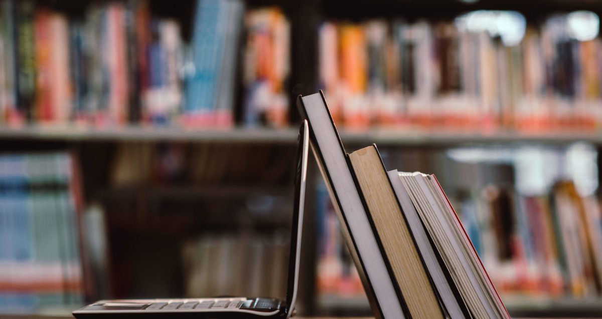 laptop computer and book on workplace in library room,Education learning Concept